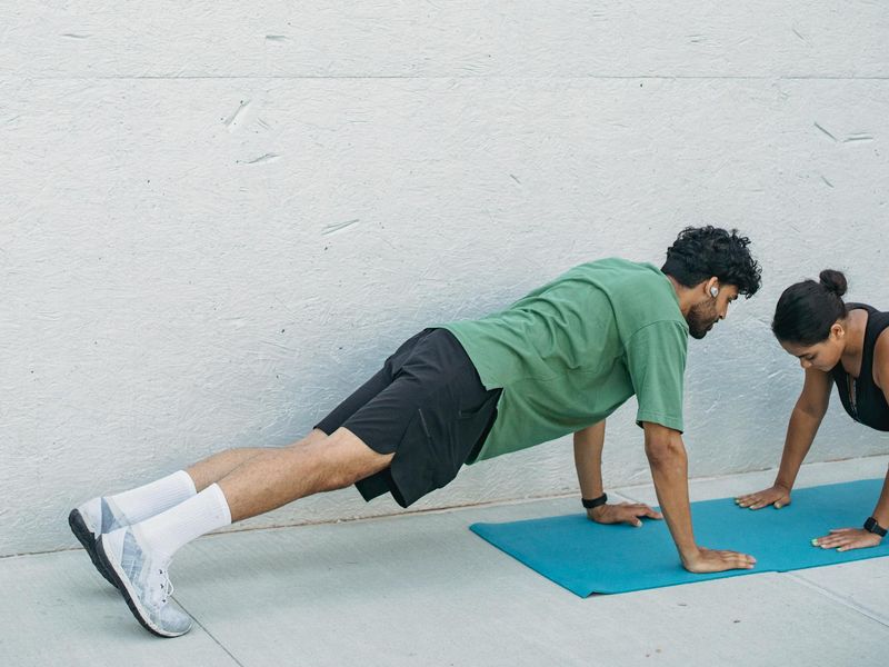 Man in a focused plank position on a dark mat.