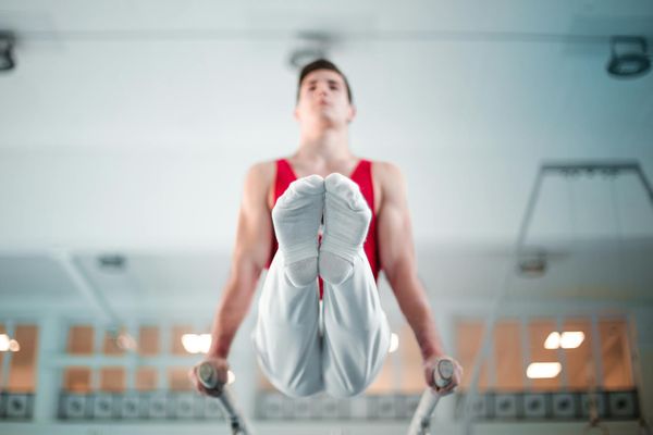 Man performing a controlled stretching exercise in a minimalist gym.